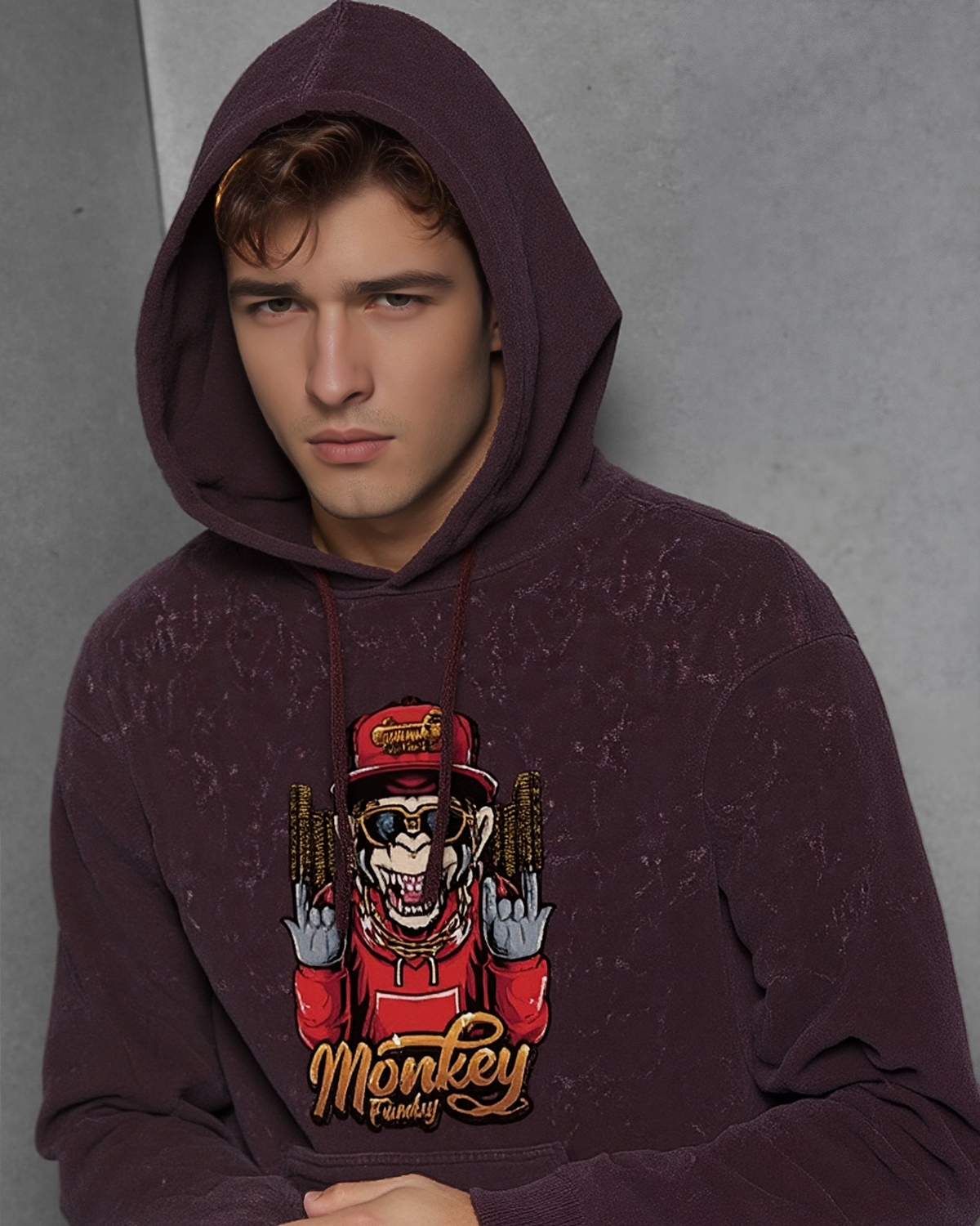 Person wearing a maroon hoodie with a graphic design on a gray background