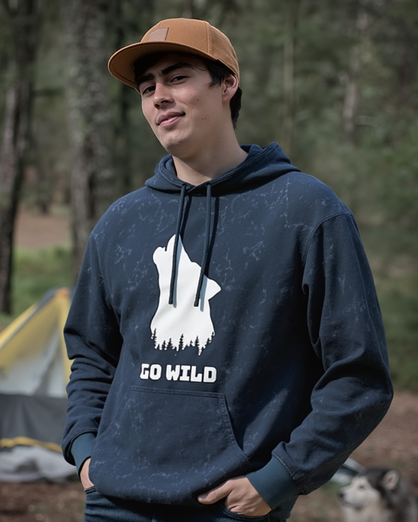 Man wearing a navy hoodie with 'Go Wild' graphic in a forest setting