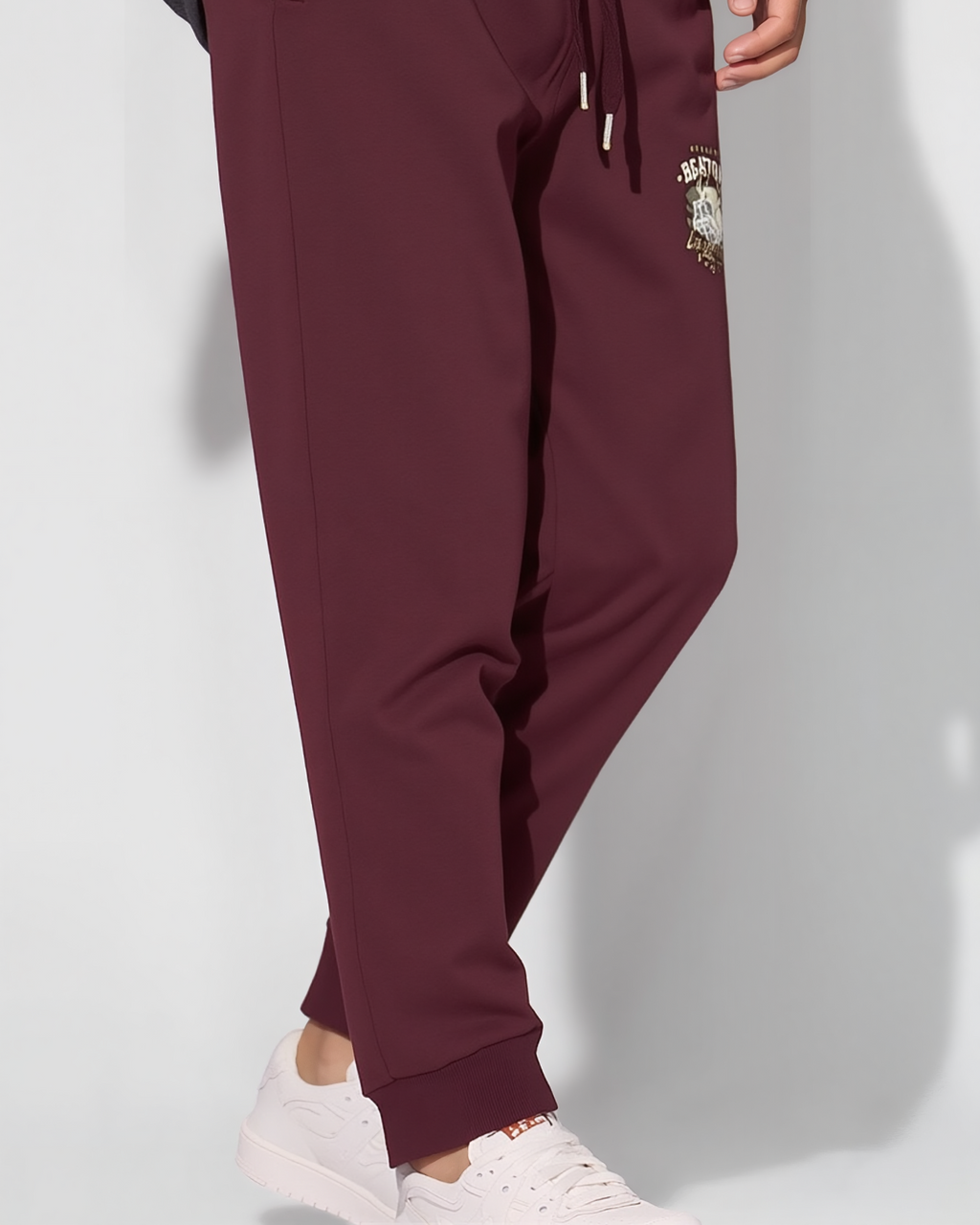 Maroon jogger pants with a logo on a white background