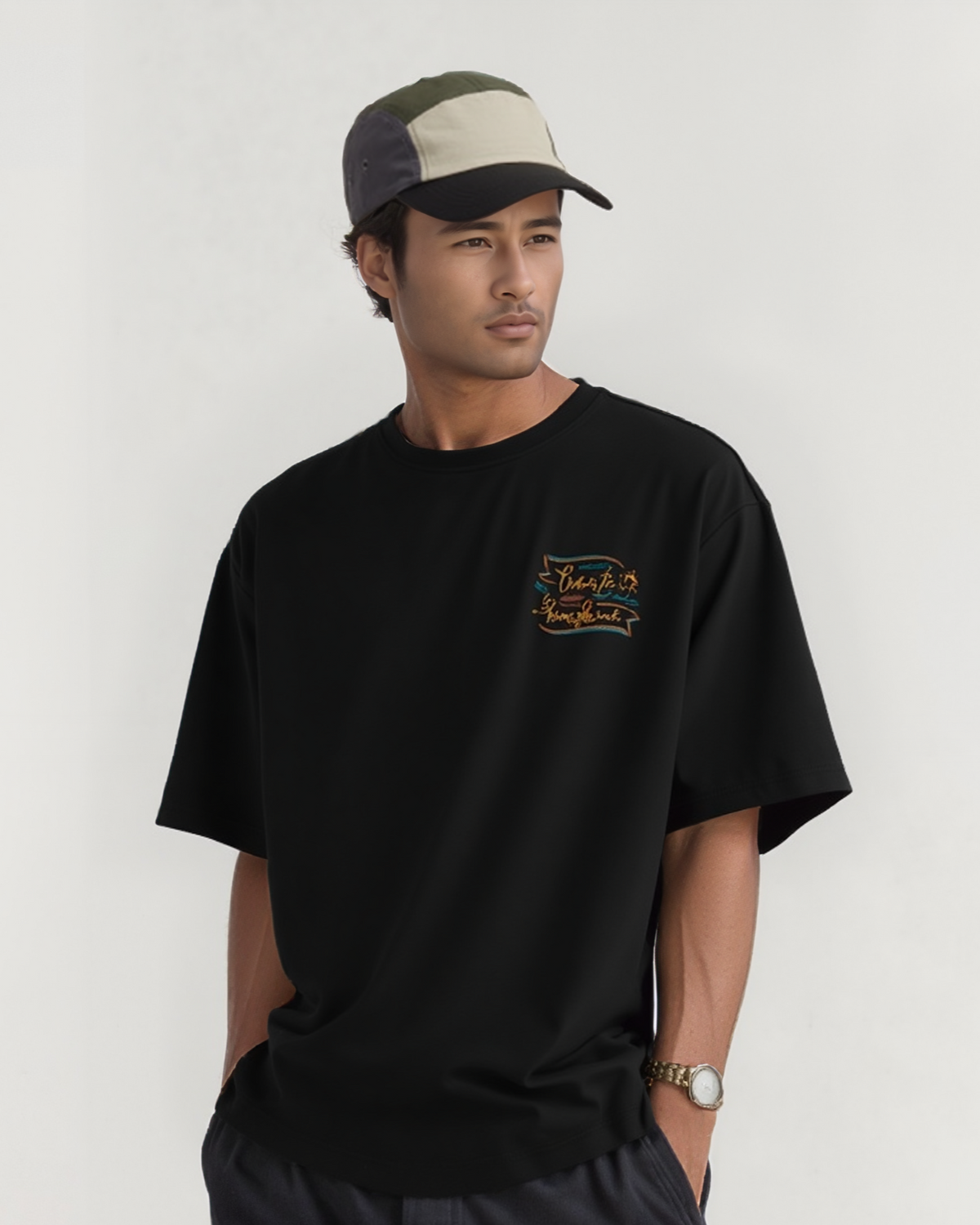 Man wearing a black t-shirt with a logo and a cap on a white background
