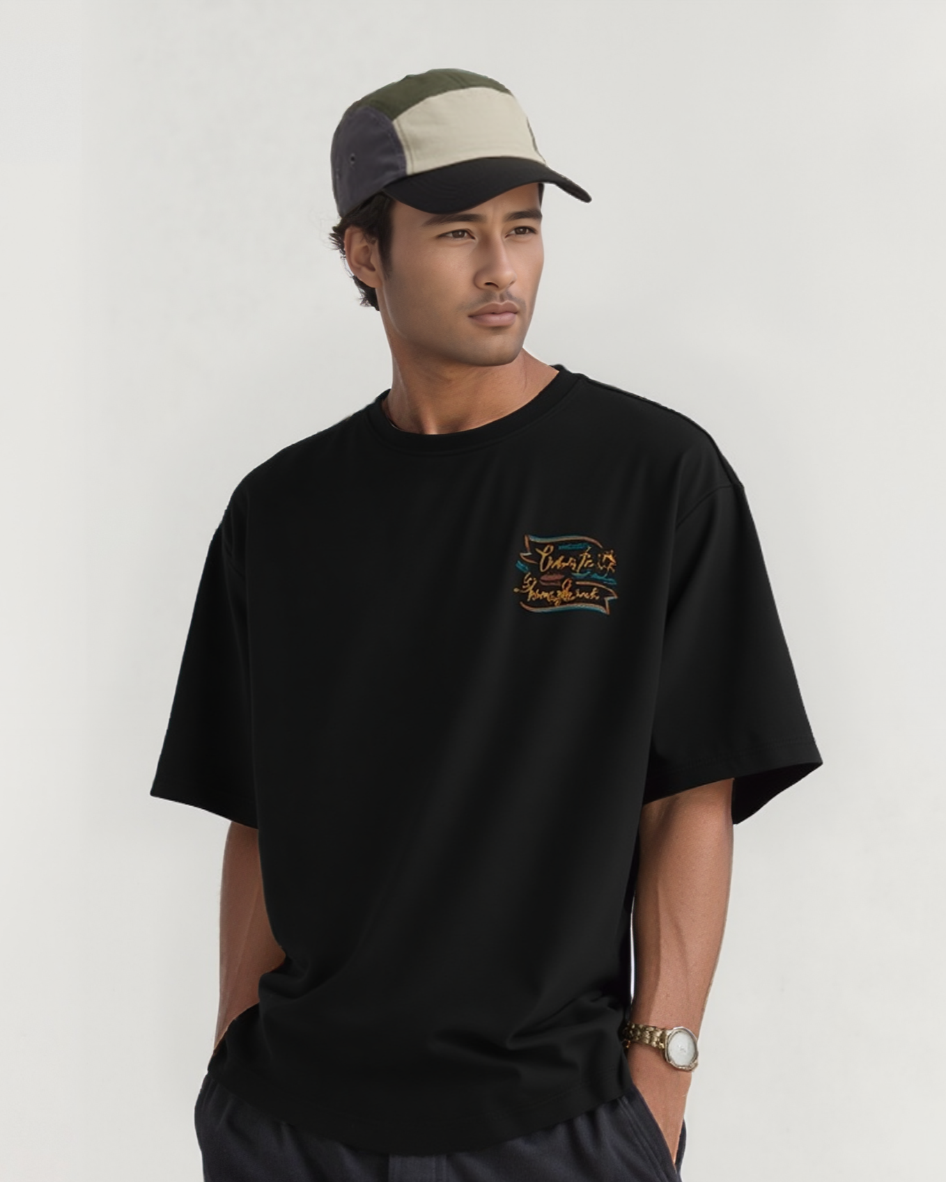 Man wearing a black t-shirt with a logo and a cap on a white background