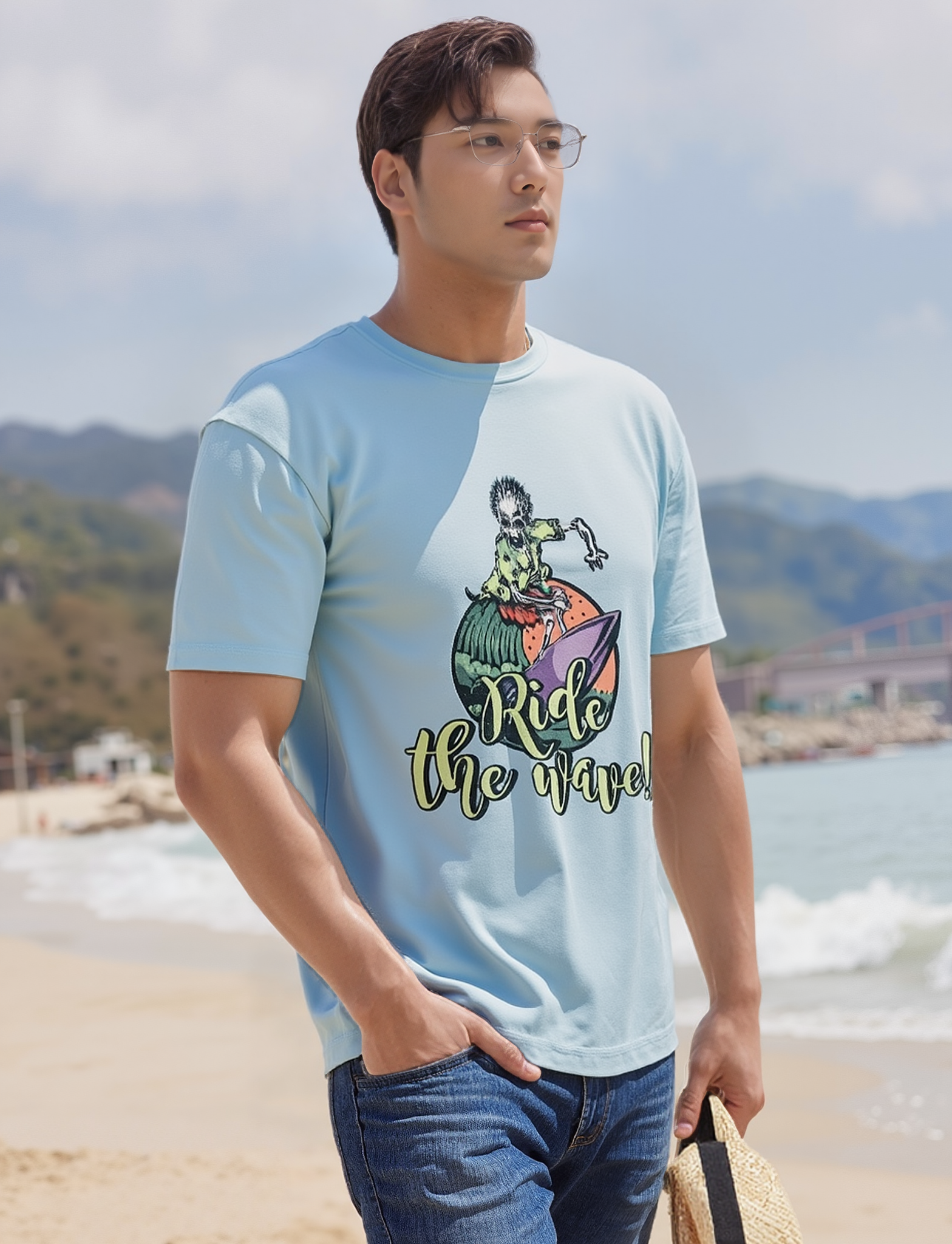 Man wearing a light blue t-shirt with a graphic design on a beach